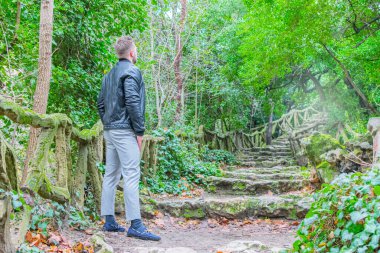 Parkta merdivenlerden yukarı bakan genç bir adam.