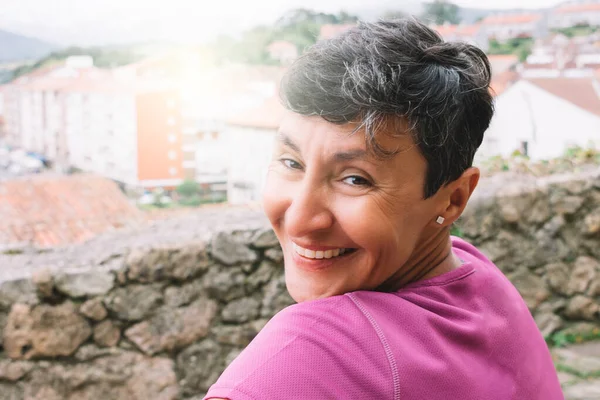 Kameraya dönüp gülümseyen bir kadın portresi.