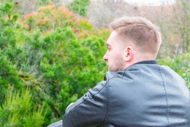 Parkta arkadan genç bir adamın yakın portresi.