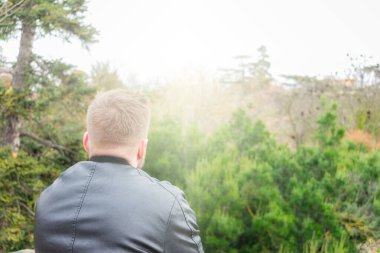 Arkadan gökyüzündeki ışığa bakan genç bir adam. Motivasyon ve din kavramı