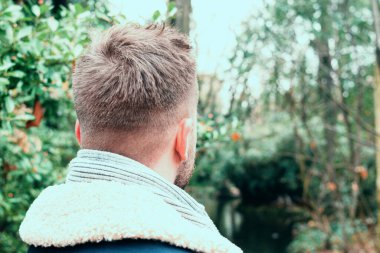 Parkta arkadan genç bir adamın yakın portresi.