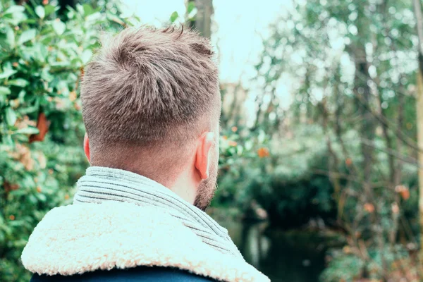 Parkta arkadan genç bir adamın yakın portresi.