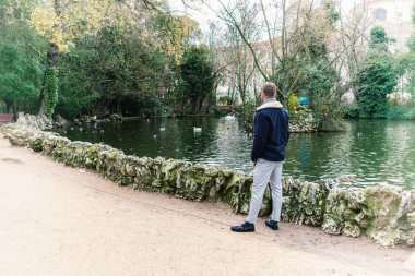 Çekici, sarışın, sakallı bir adam gölün kenarında.