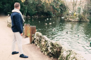 Çekici, sarışın, sakallı bir adam gölün kenarında.