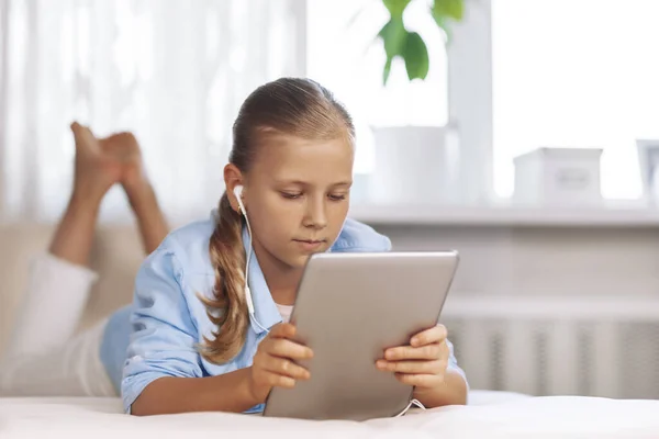 Chica adolescente feliz con los ojos azules en una sala de luz, se sienta con una tableta y se comunica mediante una videollamada. Educación en línea, aprendizaje en línea. —  Fotos de Stock