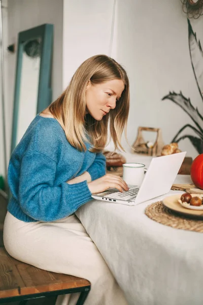 Menina loira bonito trabalhando de manhã em um laptop e beber café. Trabalho online, freelance, distância social — Fotografia de Stock