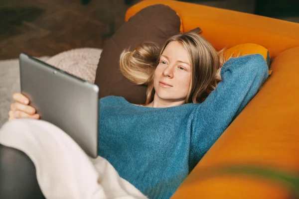 거실의 소파에 태블릿으로 영화를 여자가 시간을 알약을 사용하여 친구들과 의사소통을 — 스톡 사진