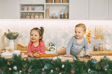 İki sevimli bebek mutfakta oynuyorlar ve bayram hediyelerini hazırlıyorlar. Noel ve Yeni Yıl Arifesi