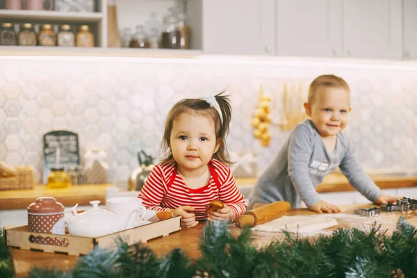 Two adorable babies play in the kitchen and help prepare holiday treats. Christmas and New years eve — Stock Photo, Image