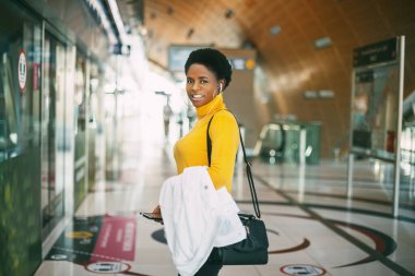 Metro istasyonunda çekici bir Afrikalı kadının portresi. Kız gülümsüyor ve kameraya bakıyor..