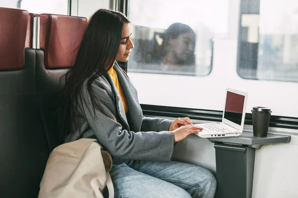 Freelance girl sitting on a train with a laptop. Modern technology and networking.