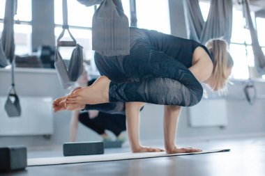 Spor salonunda yoga yapan güzel atletik genç bir kadın. Kız amuda kalkıyor, yandan bakıyor.