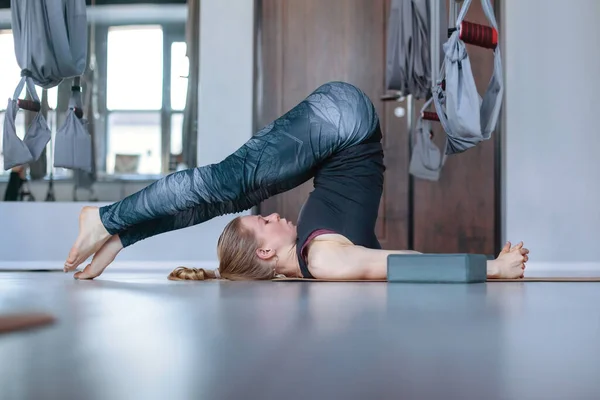 Una giovane donna attraente è impegnata nello yoga. Una ragazza in posa di betulla in una classe di Aero yoga — Foto Stock