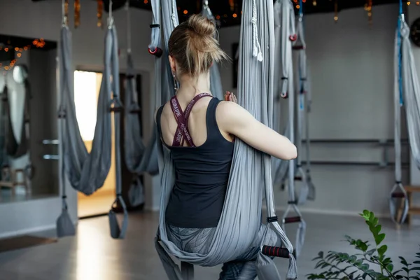 Una giovane donna medita su un'amaca in uno studio di yoga anti-gravità, il concetto di armonia e consapevolezza. Vista posteriore, spazio per il testo — Foto Stock