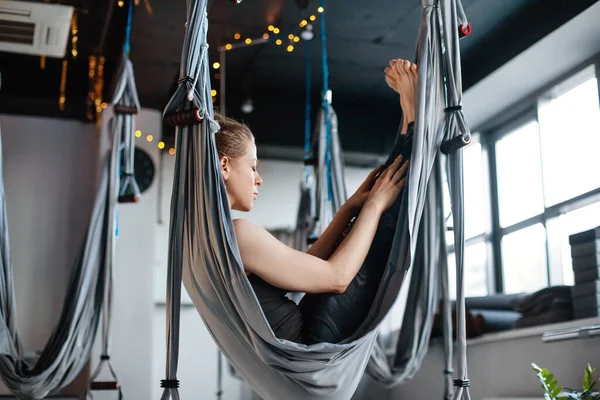 Una giovane donna attraente medita mentre si siede in un hammock dopo una classe aerea di yoga. Il concetto di armonia e consapevolezza. Stile di vita sano, riposo, relax. — Foto Stock