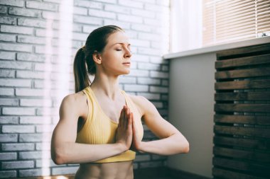 Sarışın bir kız fitness dersinden sonra dinleniyor ve meditasyon yapıyor. Spor ve sağlıklı yaşam tarzı kavramı. Yoga, meditasyon.
