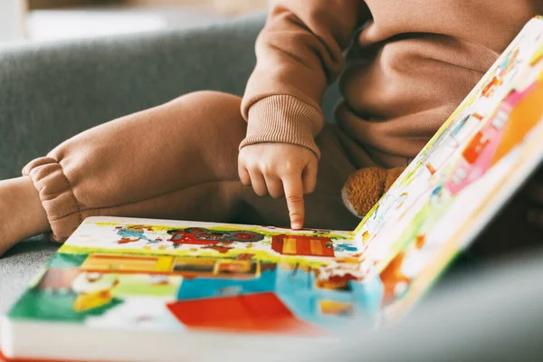 Gros plan d'un livre éducatif pour enfants avec des images colorées dans les mains d'une petite fille. Développement, éducation, enfance — Photo