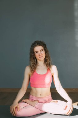 Güzel bir kız sınıftaki nilüfer pozisyonunda yoga minderinde oturur. Spor, spor, yoga. Metin için boşluk