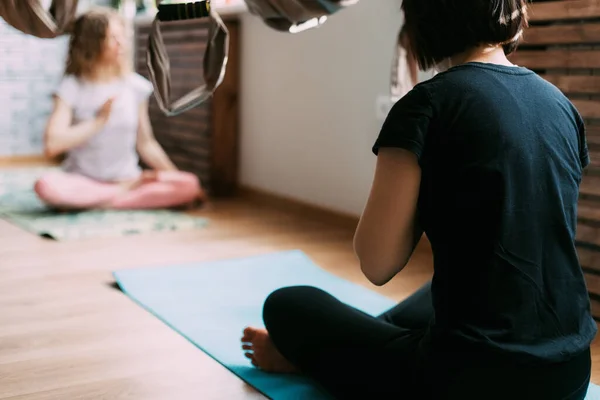 Due donne siedono su un tappeto in una classe di yoga e meditano dopo un allenamento. Riposo, relax, meditazione — Foto Stock