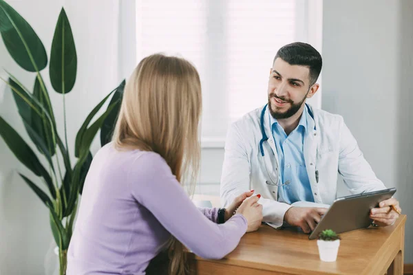 Erkek doktor hastaya danışır, hastalığı hakkında bilgi verir ve muayene hakkında konuşur..