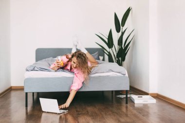 Güzel sarışın kadın sabah uyanıp hafta sonunun tadını çıkardıktan sonra yatakta meyve suyu içer.