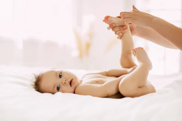 Eine junge Mutter massiert sanft die Beine ihrer Kinder. Kinderbetreuung, Kindheit, Mutterschaft — Stockfoto