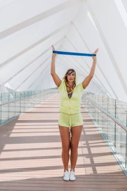 A sporty girl does exercises to strengthen her arm muscles with an outdoor expander. Sports training for girls