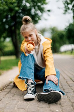 Parkta yürürken dondurmalı tatlı sarışın bir kızın portresi. Çocuk dışarıda.