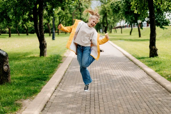 Seorang gadis remaja berjalan di taman melompat dengan es krim di tangannya. Anak di luar — Stok Foto