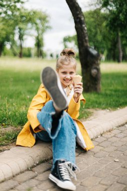 Parkta yürürken dondurmalı komik sarışın bir kızın portresi. Çocuk dışarıda.