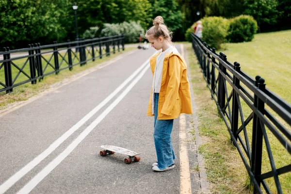 Gelukkig tiener meisje leren naar rijden een skateboard in de stad park. — Stockfoto