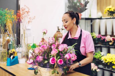 Çiçekçide buket yapan genç bir kızın portresi..