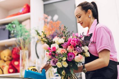 Çiçekçide bir çiçekçi kız tatil için bir buket yapar. Aile işi, güzel çiçek aranjmanı..