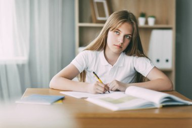 Bir lise öğrencisi bir kitaptan notlar alır, genç bir kız ödevini yapar ve derslere hazırlanır. Eğitim, eğitim, ödev