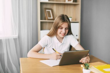 Çekici bir öğrenci çevrimiçi bir ders çalışıyor ve sınava bir tabletle hazırlanırken notlar alıyor. Eğitim ve terbiye kavramı, sınavlara hazırlık