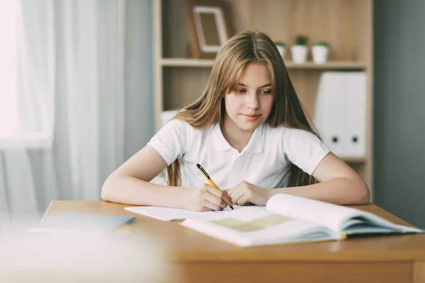 Un estudiante de secundaria toma notas de un libro, una adolescente hace su tarea y se prepara para las lecciones. Educación, formación, tareas — Foto de Stock