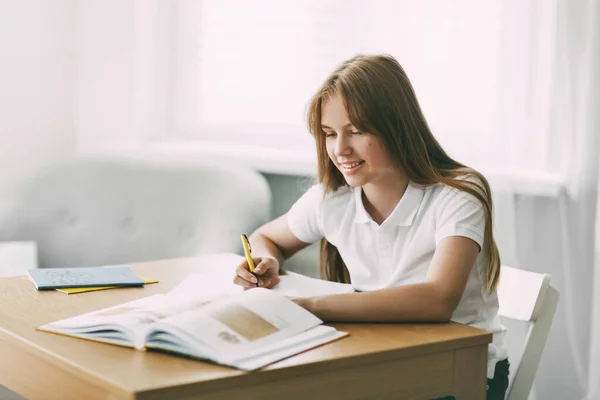 Un estudiante de secundaria toma notas de un libro, una adolescente hace su tarea y se prepara para las lecciones. Educación, formación, tareas — Foto de Stock