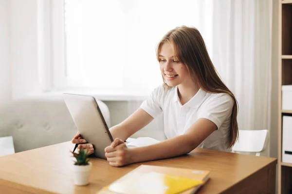그 소녀는 집에서 디지털 태블릿으로 공부하고 학교에서 숙제를 합니다. 온라인 교육을 배우는 거리 — 스톡 사진