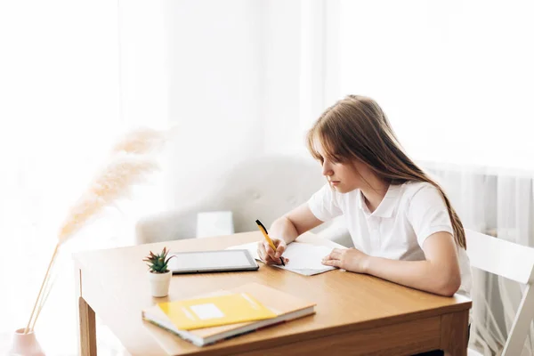 Dospívající dívka si dělá domácí úkoly sama. Koncept vzdělávání a výchovy, domácí úkoly — Stock fotografie