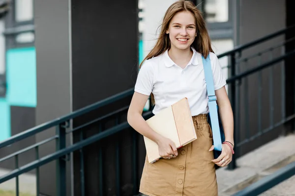 Retrato de una estudiante sonriente con un libro y una mochila camino a la universidad — Foto de Stock