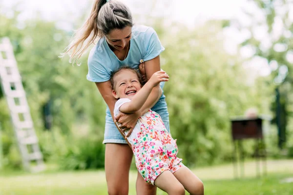 一位年轻的母亲和她可爱的小女孩在一个阳光灿烂的花园里玩得很开心。幸福的童年和母亲的概念 — 图库照片