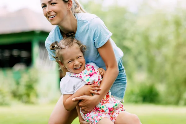 Een jonge moeder en haar schattige dochtertje hebben plezier in een zonnige tuin. Het concept van een gelukkige jeugd en een gelukkig moederschap — Stockfoto