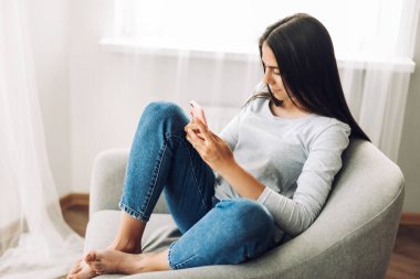 Güzel bir kız elinde telefonla bir sandalyede oturuyor, mesajlar yazıyor, alışverişler yapıyor, görüşler yapıyor ve sosyal ağlarda paylaşımlar yayınlıyor. Sosyal medya, online iletişim