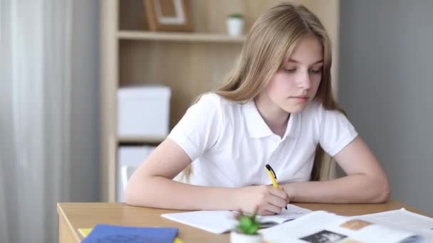 Student střední si dělá poznámky z knihy, dospívající dívka si dělá úkoly a připravuje se na lekce. Vzdělání, výcvik, domácí úkoly. — Stock video