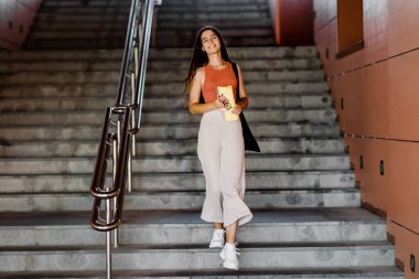 Elinde klasör olan bir kız merdivenlerden inip sınıfa gidiyor.