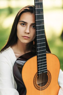 Parkta gitar çalan güzel bir müzisyen kızın portresi. Kız-müzisyen, müzik, hobi. Müzik konsepti