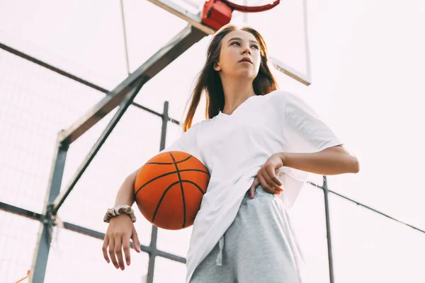 Porträtt av ung kvinnlig basketspelare. Vacker tonårstjej som spelar basket. i sportkläder som spelar basket — Stockfoto