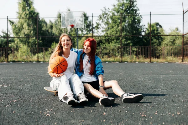 Ein paar Teenager-Mädchen auf einem Sportplatz mit Basketball-Lifestyle entspannen sich nach einem Spiel und unterhalten sich. Das Konzept von Sport und gesundem Lebensstil — Stockfoto