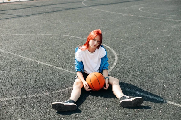 En charmig tonårstjej med basketboll vilar efter träningen. En tjej på idrottsplanen. Sport, träning, hälsosam livsstil — Stockfoto