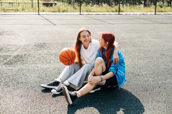 Ein paar Teenager-Mädchen auf einem Sportplatz mit Basketball-Lifestyle entspannen sich nach einem Spiel und unterhalten sich. Das Konzept von Sport und gesundem Lebensstil — Stockfoto